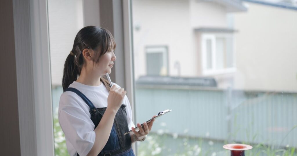 荒れた庭を見ながら悩んでいる女性の写真