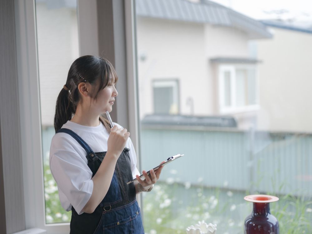 庭を眺めながら悩んでいる様子の女性の写真